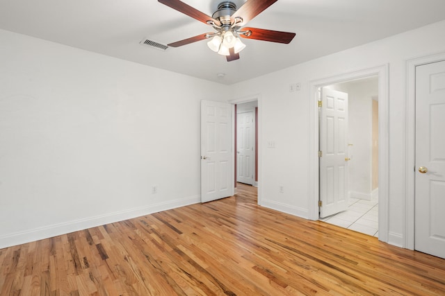 unfurnished bedroom featuring ensuite bathroom, ceiling fan, and light wood-type flooring