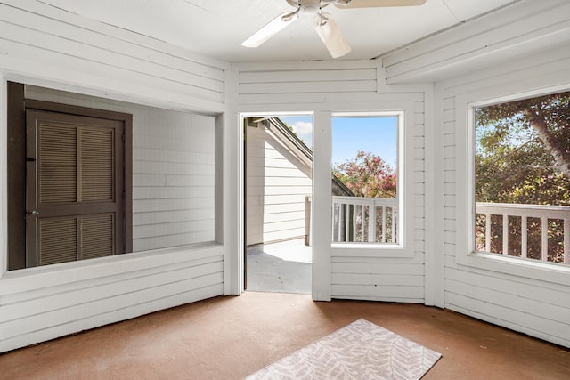 unfurnished sunroom featuring ceiling fan and a wealth of natural light