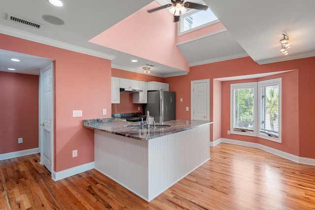 kitchen featuring white cabinets, stainless steel fridge, kitchen peninsula, crown molding, and light wood-type flooring