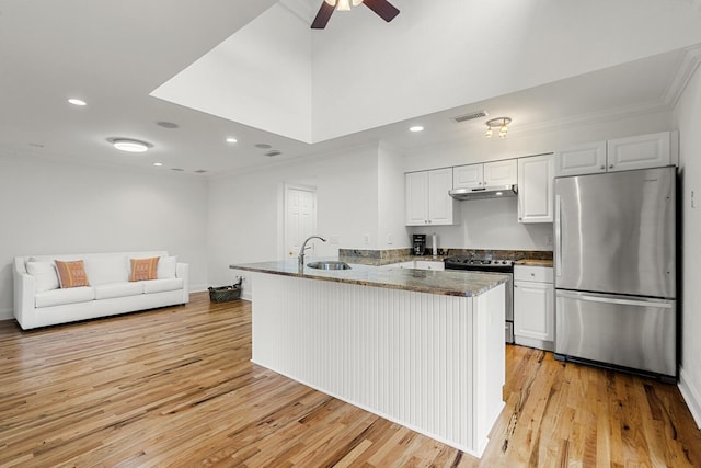 kitchen with a sink, freestanding refrigerator, light wood-type flooring, dark stone counters, and white cabinetry