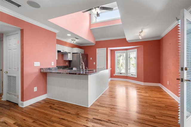 kitchen with stainless steel refrigerator, ornamental molding, kitchen peninsula, and white cabinets