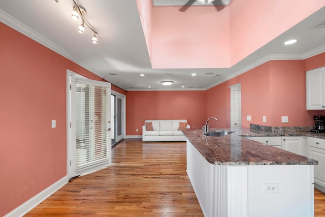 kitchen featuring sink, white cabinets, dark stone counters, light hardwood / wood-style floors, and kitchen peninsula