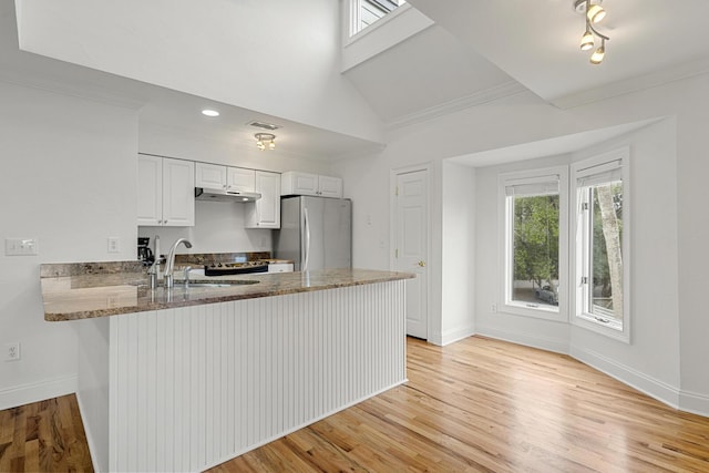 kitchen with a sink, light wood finished floors, white cabinets, a peninsula, and ornamental molding