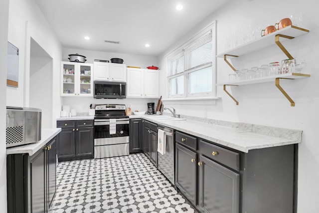 kitchen with appliances with stainless steel finishes, a sink, white cabinetry, open shelves, and light flooring