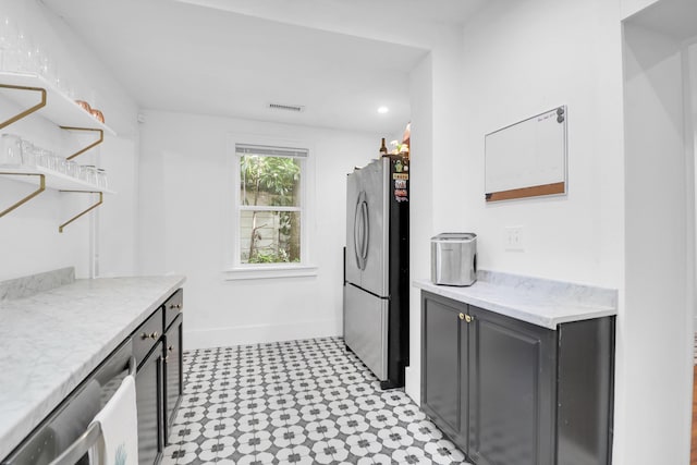 kitchen with freestanding refrigerator, open shelves, light floors, baseboards, and light stone countertops