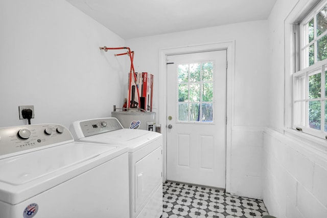 clothes washing area with healthy amount of natural light, independent washer and dryer, and water heater
