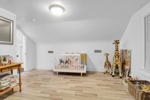 bedroom featuring light wood-style floors, vaulted ceiling, and baseboards