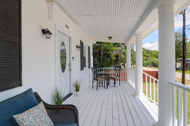 wooden terrace with a porch and outdoor dining area