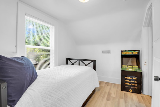 bedroom featuring wood finished floors, lofted ceiling, and baseboards