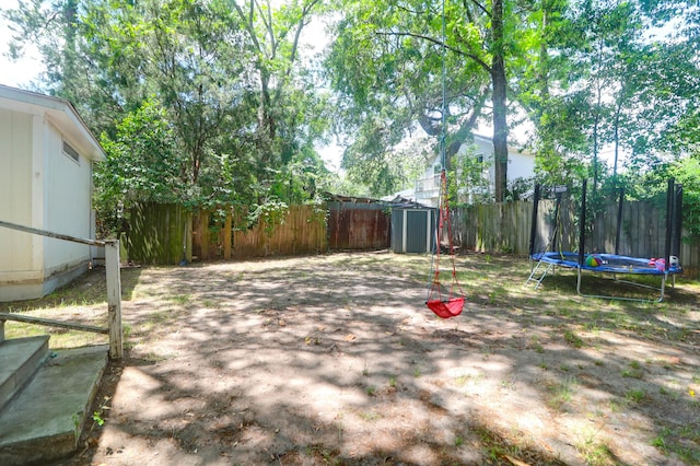 fenced backyard with a storage shed, a trampoline, and an outbuilding