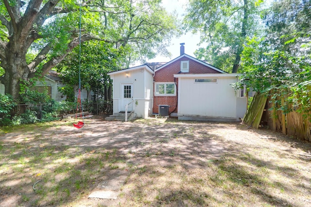 rear view of property with brick siding, fence, a chimney, and central air condition unit
