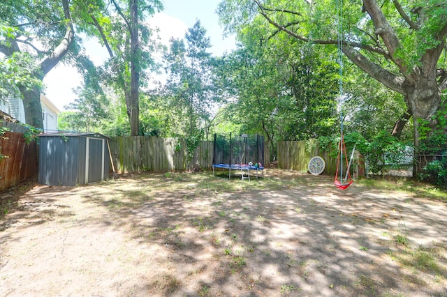 fenced backyard featuring a storage shed, an outbuilding, and a trampoline