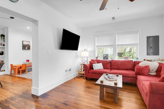 living area featuring electric panel, hardwood / wood-style floors, a ceiling fan, and baseboards