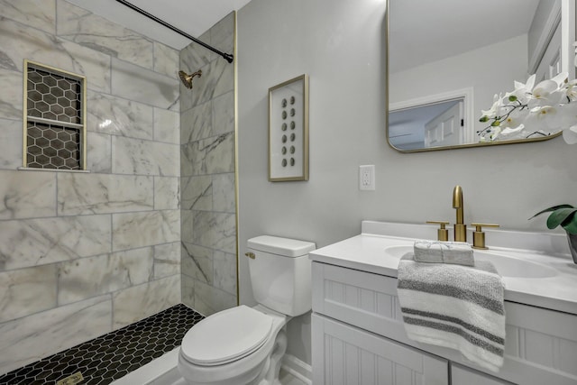 bathroom with toilet, a tile shower, and vanity