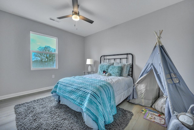 bedroom featuring baseboards, visible vents, ceiling fan, and wood finished floors