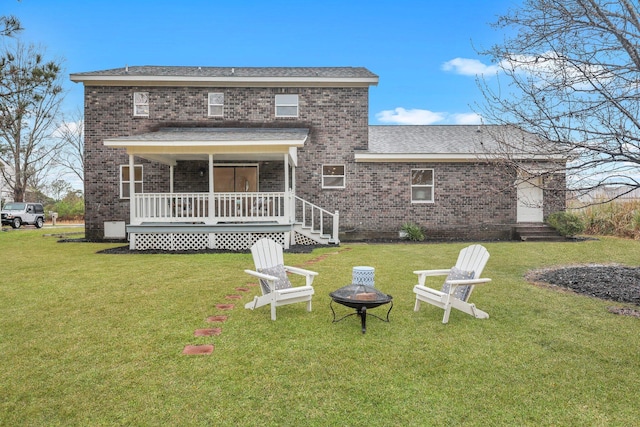 rear view of house with a fire pit, a yard, brick siding, and covered porch