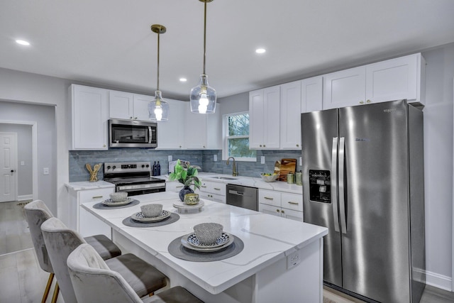 kitchen with light stone countertops, white cabinetry, appliances with stainless steel finishes, backsplash, and a center island