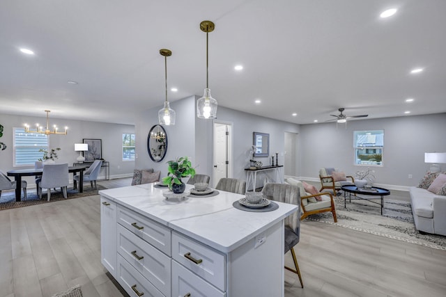 kitchen with a breakfast bar, a center island, recessed lighting, open floor plan, and white cabinets