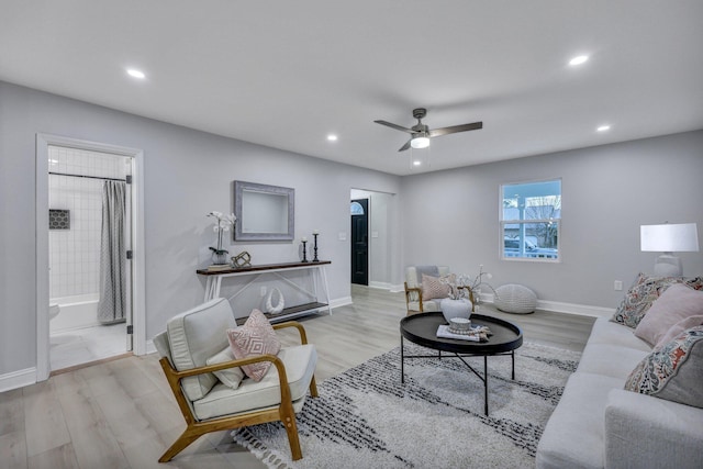 living area with light wood-style floors, ceiling fan, and baseboards