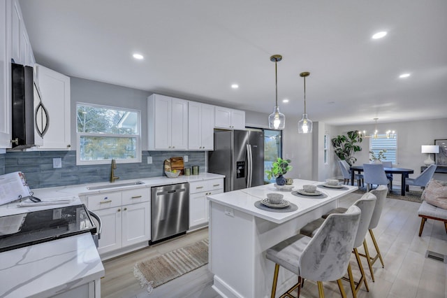 kitchen featuring white cabinetry, appliances with stainless steel finishes, backsplash, and a sink