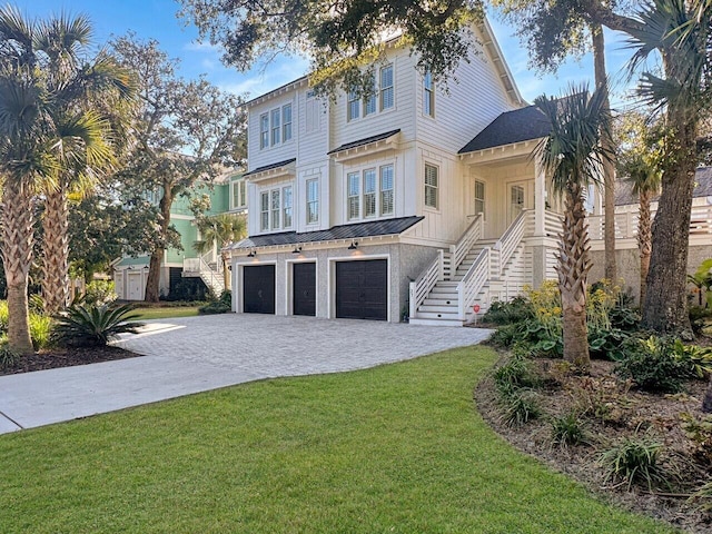 view of front of property with a garage, stairway, a standing seam roof, decorative driveway, and a front lawn