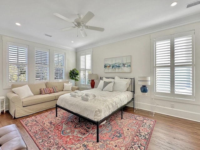 bedroom featuring recessed lighting, wood finished floors, visible vents, baseboards, and crown molding