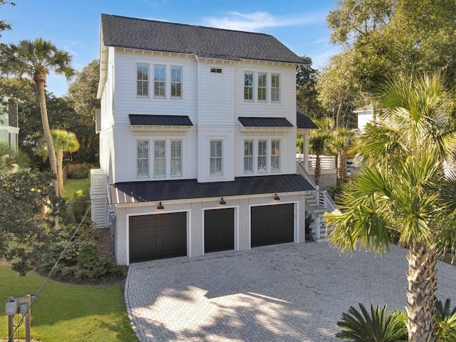 view of front of home featuring metal roof, a garage, stairs, decorative driveway, and a standing seam roof