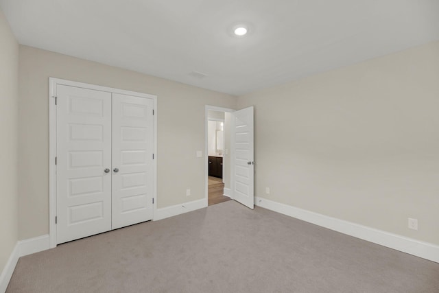 unfurnished bedroom featuring light carpet and a closet