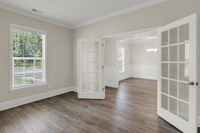 unfurnished room featuring a notable chandelier, crown molding, hardwood / wood-style floors, and french doors