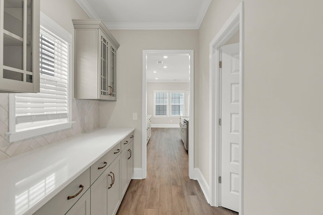 bar featuring tasteful backsplash, ornamental molding, light hardwood / wood-style floors, and gray cabinetry