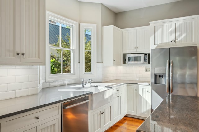707 Royall Ave, Mount Pleasant, SC 29464 - kitchen featuring stainless steel appliances, dark stone countertops, light wood finished floors, white cabinetry, and backsplash