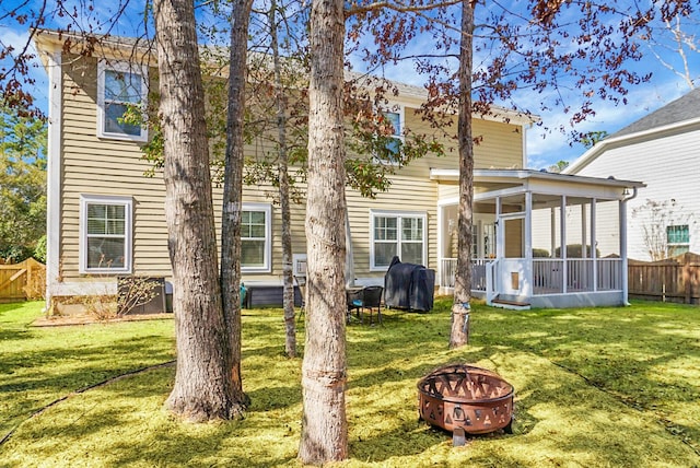 rear view of house featuring an outdoor fire pit, a yard, and a sunroom