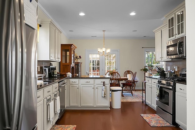 kitchen with kitchen peninsula, appliances with stainless steel finishes, tasteful backsplash, and pendant lighting