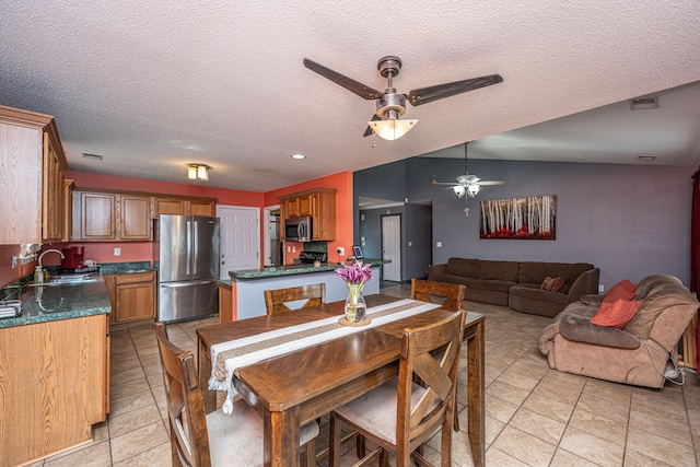 tiled dining room with vaulted ceiling, ceiling fan, sink, and a textured ceiling