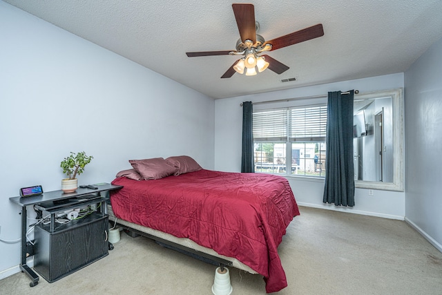 bedroom featuring a textured ceiling, ceiling fan, and light carpet