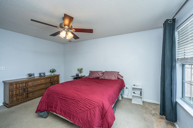 bedroom featuring a textured ceiling, light colored carpet, and ceiling fan