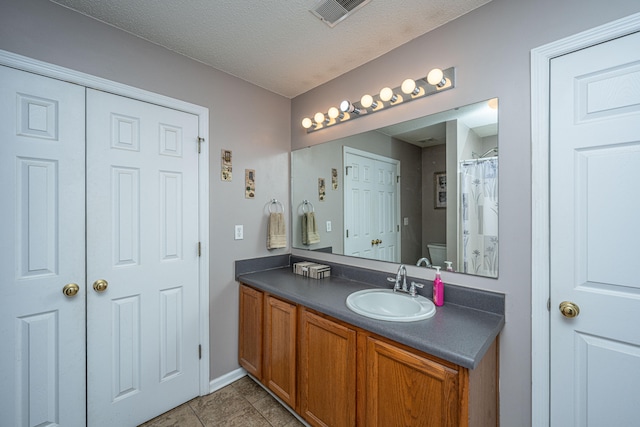 bathroom featuring vanity, tile patterned floors, a textured ceiling, and toilet