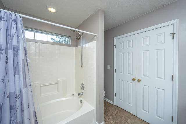 bathroom featuring tile patterned floors, toilet, shower / bath combo with shower curtain, and a textured ceiling