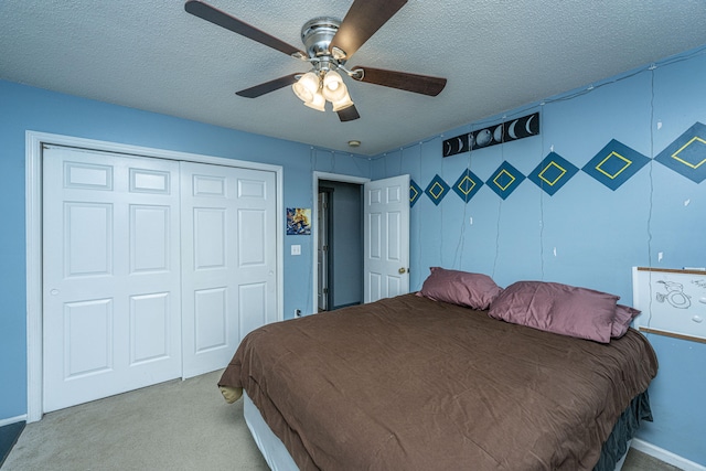 bedroom featuring a closet, a textured ceiling, light colored carpet, and ceiling fan