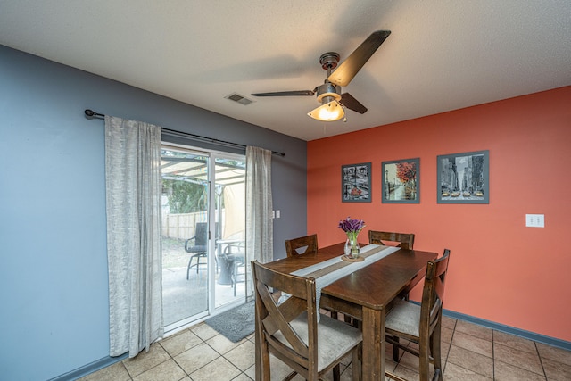 tiled dining area with a textured ceiling and ceiling fan