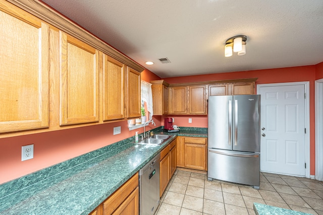 kitchen featuring a textured ceiling, light tile patterned flooring, sink, and appliances with stainless steel finishes