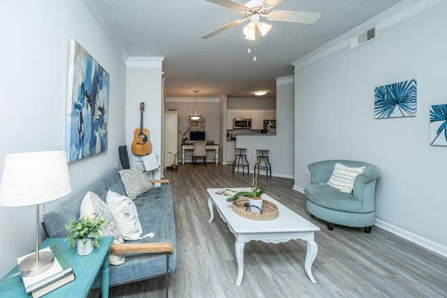 living room featuring crown molding, a textured ceiling, wood-type flooring, and ceiling fan