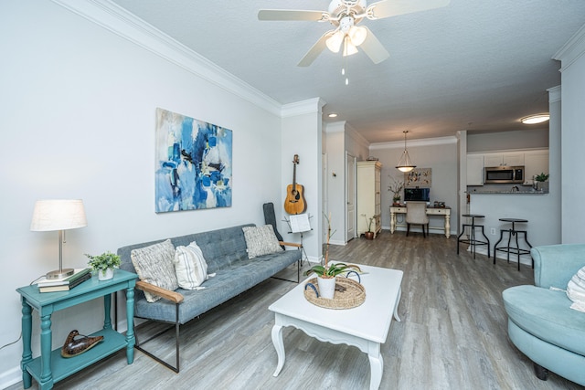 living room with ornamental molding, a textured ceiling, wood-type flooring, and ceiling fan