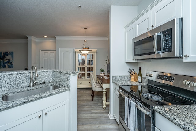 kitchen with appliances with stainless steel finishes, sink, white cabinets, crown molding, and light hardwood / wood-style flooring