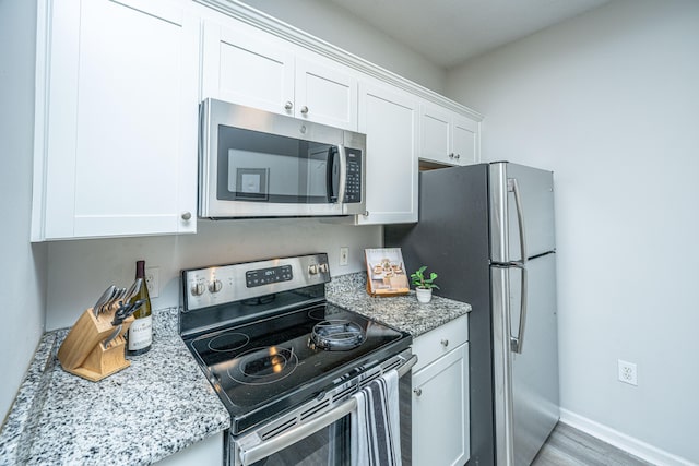 kitchen featuring light stone countertops, light hardwood / wood-style floors, appliances with stainless steel finishes, and white cabinets