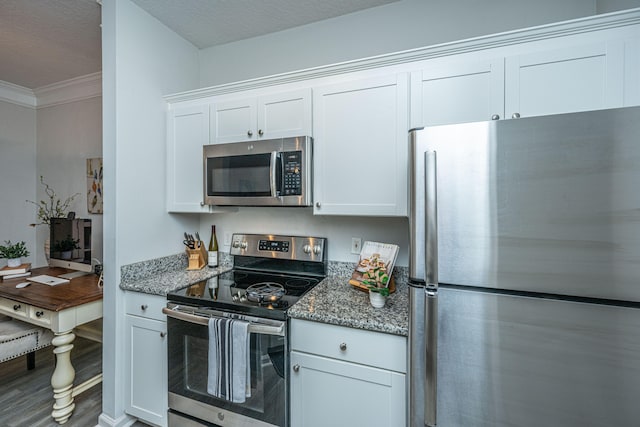 kitchen featuring appliances with stainless steel finishes, white cabinets, dark stone countertops, and wood-type flooring