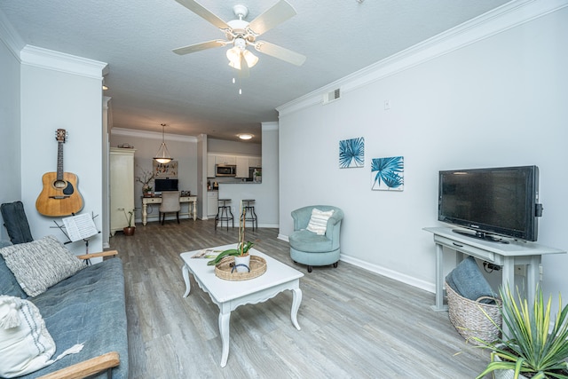 living room featuring ceiling fan, ornamental molding, a textured ceiling, and hardwood / wood-style floors