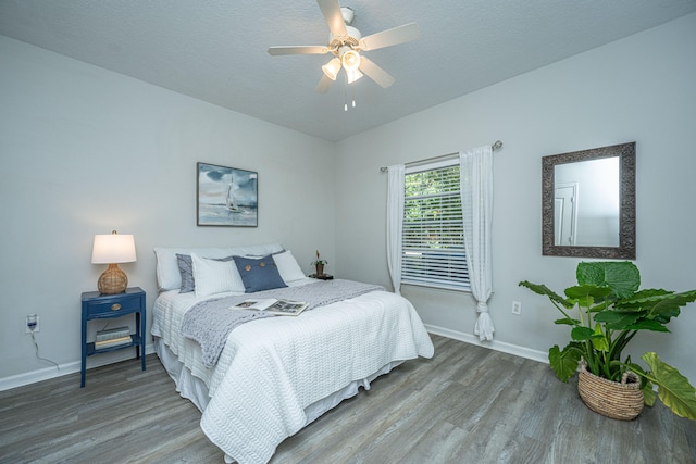 bedroom with ceiling fan, wood-type flooring, and a textured ceiling