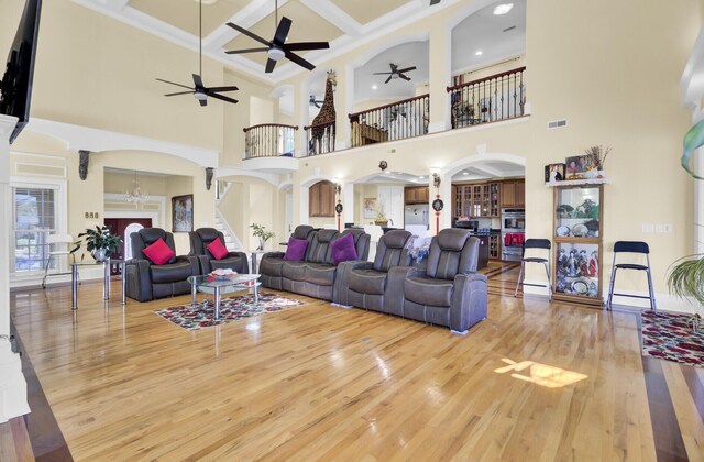 living area featuring wood finished floors, a ceiling fan, coffered ceiling, visible vents, and arched walkways