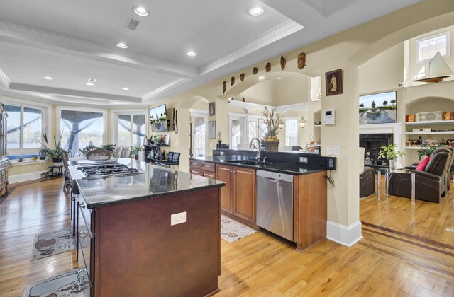 kitchen featuring a kitchen island, open floor plan, arched walkways, stainless steel appliances, and a sink